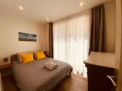 a bedroom with a bed with yellow pillows and a window at Bright airy family style 7 min walk to beach in Caldes d'Estrac