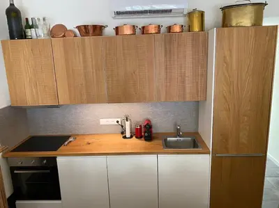 a small kitchen with a sink and wooden cabinets at Bright airy family style 7 min walk to beach in Caldes d'Estrac