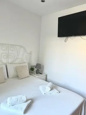 a white bed with two towels and a flat screen tv at Reina apartment in Sitges in Sitges