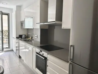a kitchen with white cabinets and stainless steel appliances at Reina apartment in Sitges in Sitges