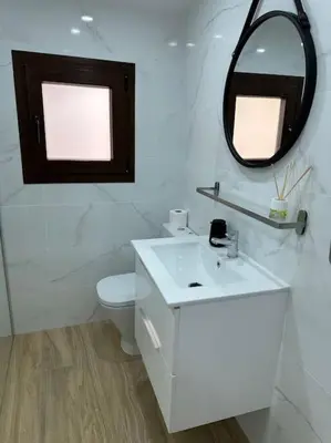 a white bathroom with a toilet and a mirror at Casa de Invitados in La Floresta Pearson