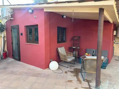 a red house with a table and a chair at Casa de Invitados in La Floresta Pearson