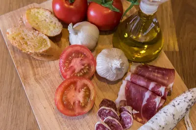 a cutting board with tomatoes onion and bread on a table at Plaza Catalunya City Center Apartments in Barcelona