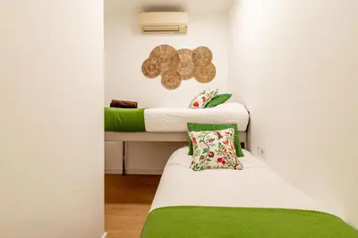 a small room with two beds with green sheets at Modern Apartment 2 rooms 15' Bcn Center - Fira Barcelona in Barcelona
