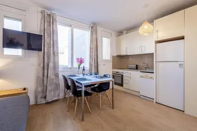 a kitchen with a table with chairs and a refrigerator at Modern Apartment 2 rooms 15' Bcn Center - Fira Barcelona in Barcelona