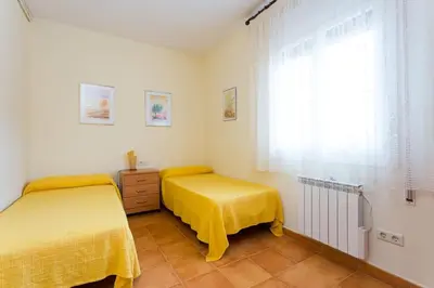 two beds in a room with yellow sheets and a window at Cal Vimón in Las Masucas