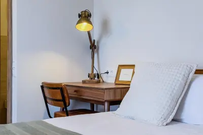 a desk with a lamp and a laptop on a bed at Apartamento exclusivo en Sant Antoni in Barcelona