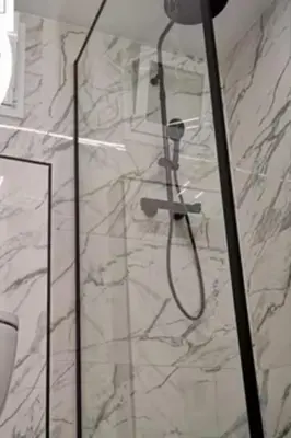 a shower in a bathroom with a marble wall at Vidanova 1 in Vilanova i la Geltrú