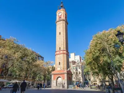 a tall tower with a clock on top of it at Renovated Apartment in Vila de Gràcia in Barcelona