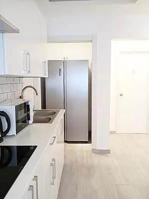 a kitchen with white cabinets and a stainless steel refrigerator at Warm Harbor in Santa Coloma de Gramanet