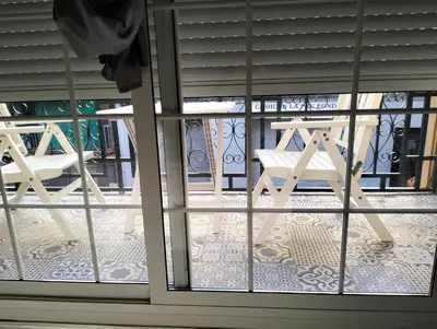 a window with a table and a bench on a balcony at Warm Harbor in Santa Coloma de Gramanet