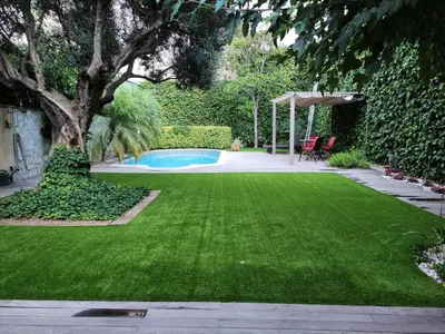 a yard with a green lawn and a swimming pool at Alojamiento independiente de invitados el Olivo in El Prat de Llobregat
