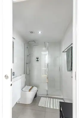 a white bathroom with a shower and a toilet at StayCampNou 1BR with Balcony in Hospitalet de Llobregat