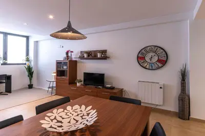 a dining room with a table and a clock on the wall at Acogedor apartamento Diagonal Mar in Barcelona