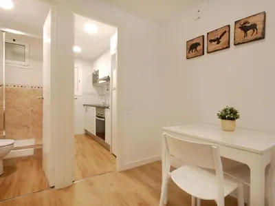a white dining room with a table and a kitchen at Lovely and cozy apartments near Barcelona in Hospitalet de Llobregat