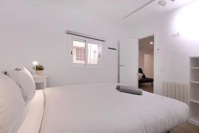 a white bedroom with a white bed and a window at Lovely and cozy apartments near Barcelona in Hospitalet de Llobregat