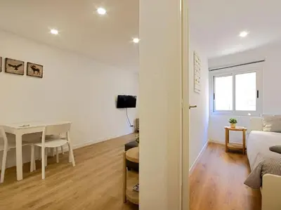 a white room with a table and a bed and a dining room at Lovely and cozy apartments near Barcelona in Hospitalet de Llobregat