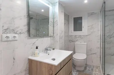 a white bathroom with a toilet and a sink at Hermoso apartamento en el centro in Barcelona