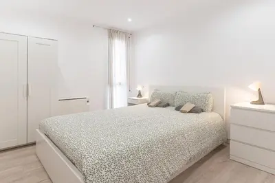 a white bedroom with a bed and a window at Hermoso apartamento en el centro in Barcelona
