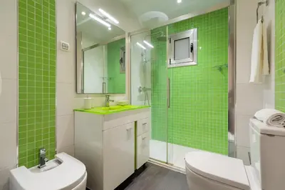 a bathroom with green tiles and a toilet and a sink at Precioso apartamento en el Centro in Barcelona
