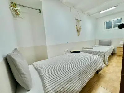 two beds in a room with striped sheets at 45 Center Basic 1 2 in Barcelona