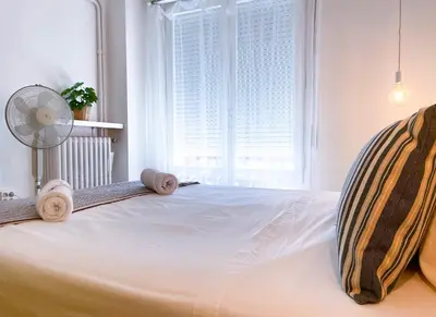a bedroom with a bed with a fan and a window at Apartment Vicente in Vilanova i la Geltrú