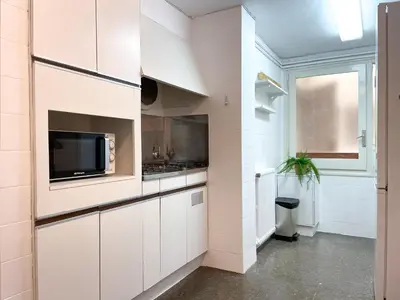 a kitchen with white cabinets and a flat screen tv at Apartment Vicente in Vilanova i la Geltrú