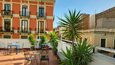 a patio with tables and chairs and palm trees at HeyLola! Hostel in Barcelona