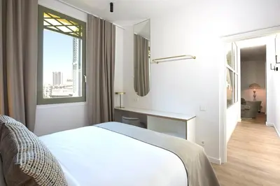 a white bedroom with a bed and a window at The Diagonal Suites Atic by Sweett in Barcelona