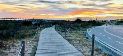 a wooden walkway next to a road with a sunset at Frente a mar salida directa playa solo 30M agua in Cubelles