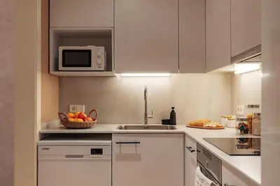 a kitchen with white cabinets and a bowl of fruit on the counter at Casa Calders in Barcelona