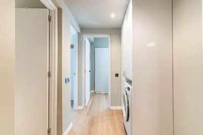 a kitchen with white walls and wood floors and a refrigerator at Villa Atardecer in Barcelona