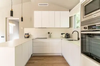 a white kitchen with white cabinets and a sink at Villa Atardecer in Barcelona
