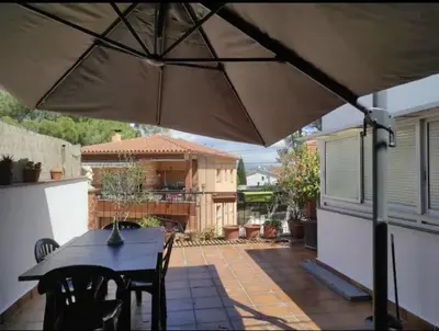a patio with a table and chairs and an umbrella at Ca La Dulcet in Gélida
