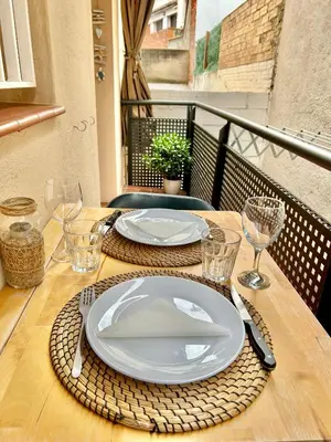a wooden table with plates and glasses on a balcony at Apartamento Sant Josep in Canet de Mar