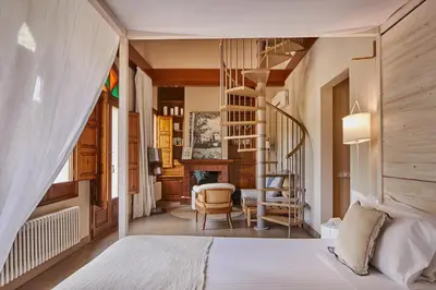 a bedroom with a bed and a spiral staircase at Mas Salagros EcoResort & SPA in Vallromanas