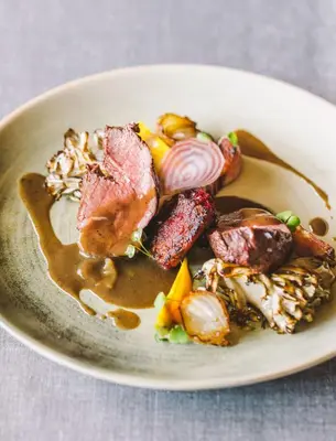a plate of food with meat and vegetables on a table at Mas Salagros EcoResort & SPA in Vallromanas