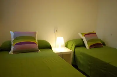 a room with two green beds and a table with a lamp at Lets Holidays Apartment Barcelona near beach in Barcelona