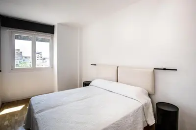 a white bedroom with a bed and a window at Suitur apartamento exclusivo céntrico Barcelona in Barcelona