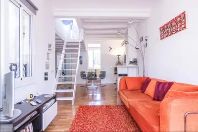 a living room with a orange couch and a staircase at Terrace Duplex at Sagrada Familia by PriorityVillas in Barcelona