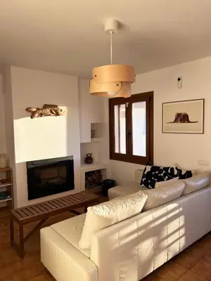 a living room with a white couch and a fireplace at Espectacular Sunny House in the beach in Cunit
