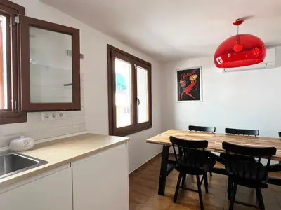 a kitchen with a wooden table and black chairs at Espectacular Sunny House in the beach in Cunit