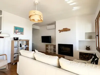 a living room with a white couch and a fireplace at Espectacular Sunny House in the beach in Cunit