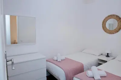 a white bedroom with two beds and a mirror at Apartamento Gaudí-Sant Pau in Barcelona
