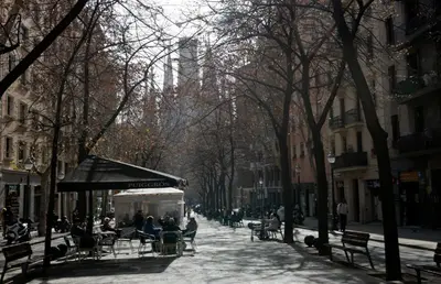 people sitting on benches on a city street with trees at Apartamento Gaudí-Sant Pau in Barcelona