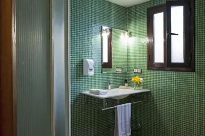 a green tiled bathroom with a sink and a mirror at AinB Las Ramblas-Guardia Apartments in Barcelona