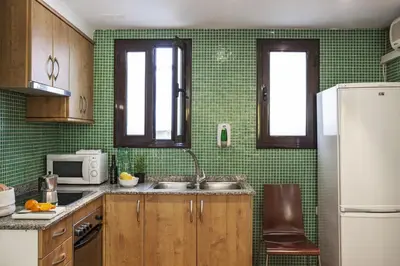 a green tiled kitchen with a sink and a refrigerator at AinB Las Ramblas-Guardia Apartments in Barcelona