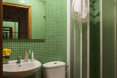 a green tiled bathroom with a toilet and a sink at AinB Las Ramblas-Guardia Apartments in Barcelona