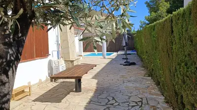 a wooden bench sitting on a sidewalk next to a hedge at Holiday Beach Home Rincón del Mar in Cunit