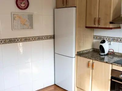 a white refrigerator in a kitchen with wooden cabinets at Casa Serenidad: Naturaleza, Jacuzzi & Parking en Cubelles - ES-332-10 in Cubelles